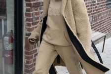 Hailey Bieber wearing a tan oversized hoodie and sweatpants, white trainers and a tan fuzzy coat for winter