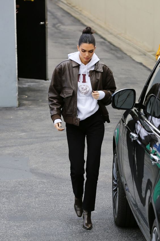 Kendall Jenner wearing a white oversized printed hoode, black trousers, brown boots and a black cropped leather jacket