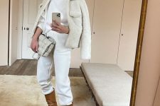 Rosie Huntington-Whiteley wearing a white turtleneck and sweatpants, brown boots, a white faux fur jacket and a creamy bag