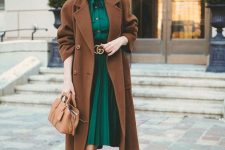 a beautiful feminine outfit with an emerald shirtdress with a plated skirt, beige boots, a brown coat and a beige bag