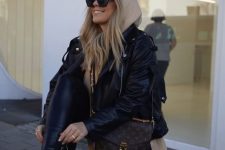 a beige oversized hoodie, a black leather jacket, black leggings, black boots and a brown printed bag