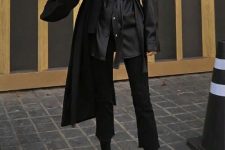 a black leather shirt with a sash, black cropped flare jeans, black sock boots and a black coat on top