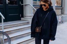 a black oversized hoodie, black leggings, a colorful printed bag and white sneakers to wear tight now