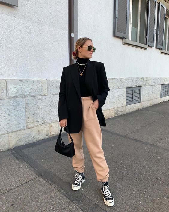 a black turtleneck, peachy sweatpants, black sneakers, an oversized blazer, layered necklaces and a black bag