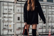 a bold and sexy look with an oversized hoodie as a dress, over the knee boots and a black bag for a daring look
