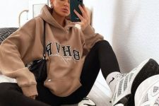 a comfy sporty outfit with a tan oversized hoodie, black leggings, white socks and trainers plus a black bag for every day