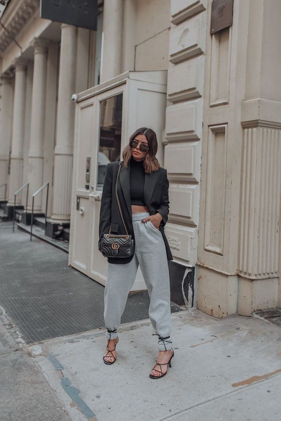 a creative look with a black cropped turtleneck, grey sweatpants, black lace up shoes, an oversized blazer and a black bag