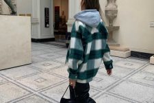a grey oversized hoodie, a white and green plaid shirt jacket, black leather trousers, white sneakers and a black bag