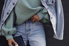 a pale green oversized hoode, blue ripped jeans and an oversized bleached blue denim jacket plus a black clutch