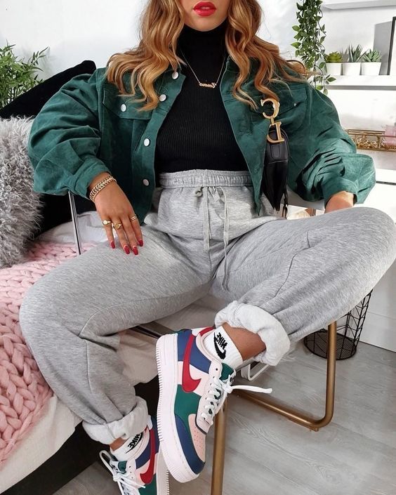 a sport chic look with a black turtleneck, grey sweatpants, colorful trainers, a green denim cropped jacket and a necklace