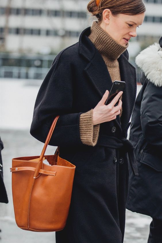 a taupe turtleneck sweater, a black coat and an amber bucket bag for a touch of color on a cold fall day