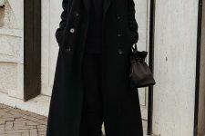 a total black look with a turtleneck, skinnies, chunky boots, a maxi coat and a bucket bag