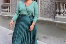 a total green look with a light green jumper, a dark green pleated maxi skirt, white trainers and a black bag