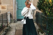 a white patterned sweater, white trainers and a bag plus a dark green plated maxi skirt for a bold contrast