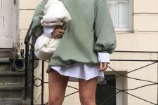 a white shirtdress, an olive green oversized sweatshirt, white boots, a white bag and a statement necklace for a trendy look
