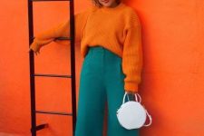 an unexpected color combo of an orange sweater, green culottes, white shoes and a white bag for a statement