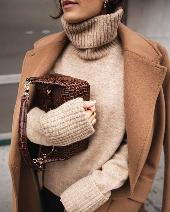 black jeans, a tan turtleneck sweater, a bege coat, a brown reptile print bag for a cold day