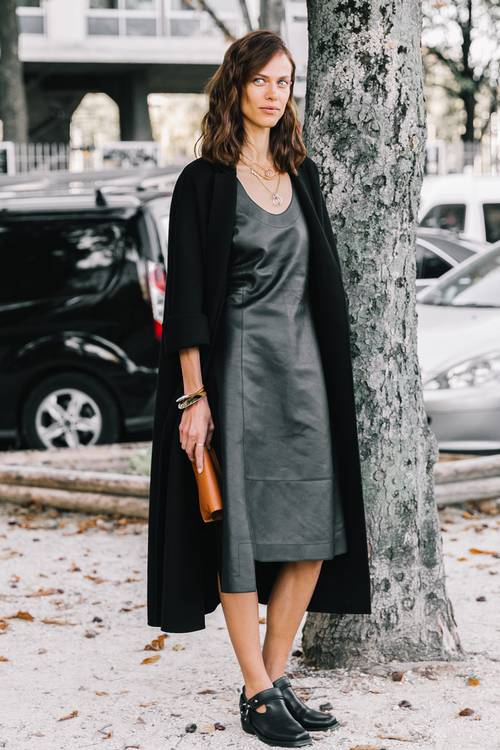 a trendy minimalist look with a black leather midi dress with an asymmetrical skirt, a long black cardigan and black shoes