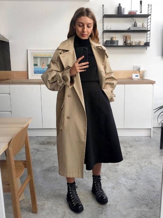 a minimalist look with a black turtleneck, an A line midi skirt, black hiking boots, a tan coat for winter