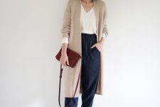 06 a stylish casual look with a white top, navy trousers, burgundy boots and a bag, a tan long cardigan