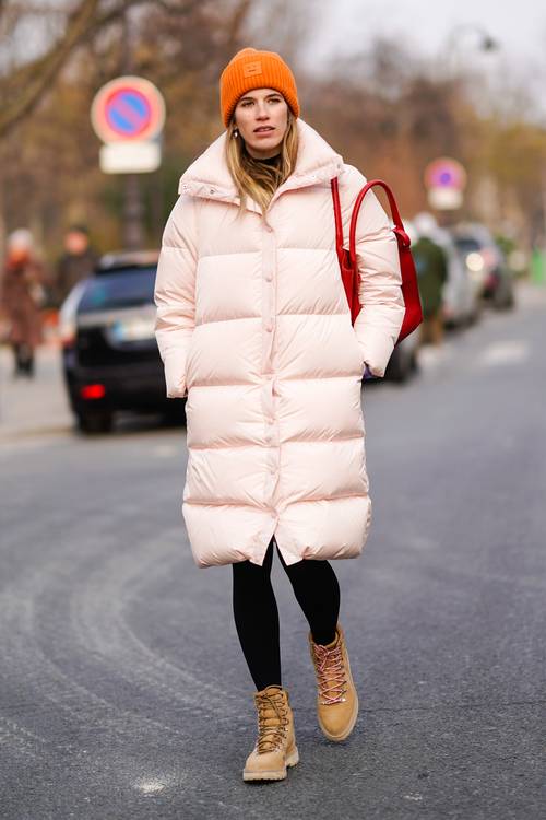 a blush puff coat, black leggings, rust colored boots, an orange beanie and a red bag