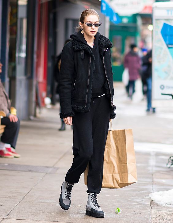 Gigi Hadid wearing a total black look with sweatpants, a hoodie, a shearling coat and hiking boots
