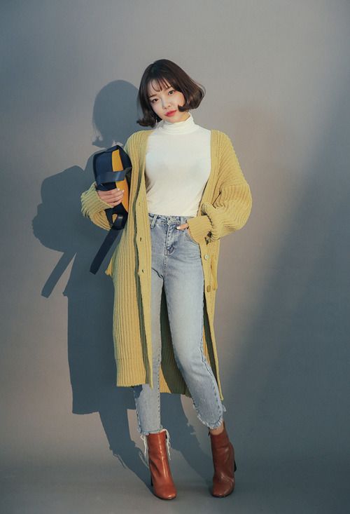 a white turtleneck, light blue jeans, burgundy ankle boots, a mustard long cardigan and a two colored bag