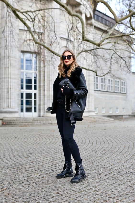 a total black look with a sweater, skinnies, combat boots, shearling coat and a small bag