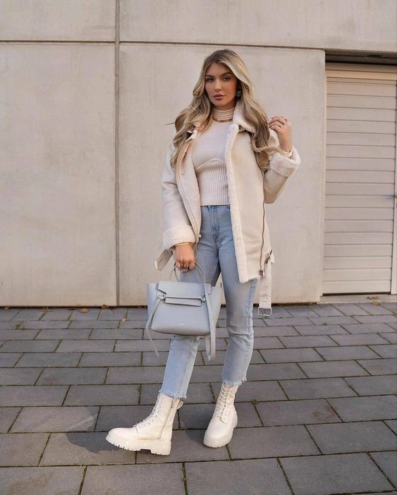 a neutral winter look with a turtleneck, light blue jeans, white combat boots and a shearling coat and a grey bag