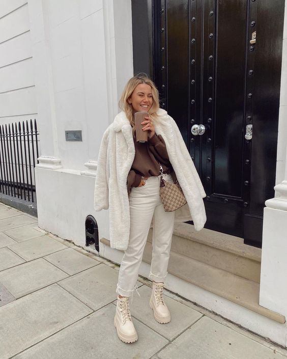a chocolate brown sweatshirt, white jeans, neutral combat boots, a white faux fur coat and a bag