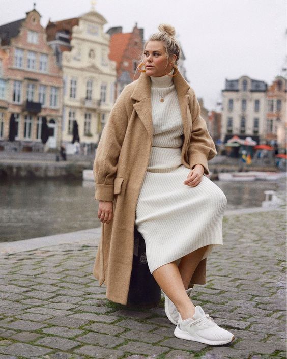a lovely winter look with a creamy midi sweater dress, a tan fuzzy coat, neutral trainers and a coin necklace