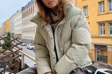 20 a pretty neutral-colored winter look with a tan sweater, grey leather trousers, a light green puffer jacket