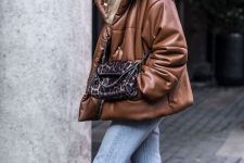 a 90s inspired winter look with a brown leather puffer jacket, light blue jeans, a printed bag and a black beanie