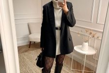 29 a chic winter outfit with a white sweaterdress, a black blazer and a belt, tights, black riding boots and a bag