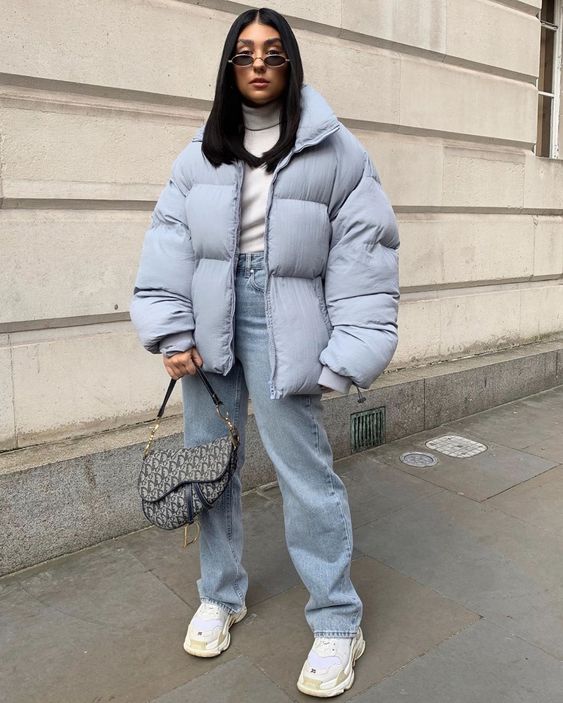 a catchy 90s look with a white turtleneck, light blue jeans, a light blue puffer jacket, a printed bag and white trainers