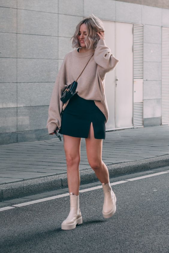 a tan jumper, a black slit mini skirt, white chunky Chelsea boots and a black mini bag
