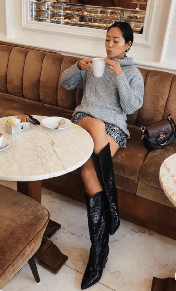 a winter outfit with a grey patterned sweater, a grey snakeskin print mini, black cowboy boots and statement earrings