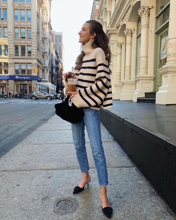 a simple and classy outfit with an oversized black and white striped sweater, light blue jeans, black heels and a black velvet bag