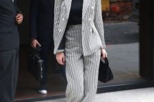 With black and white striped high-waisted palazzo pants, sunglasses, black velvet bag and black boots