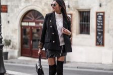 With black leather asymmetrical mini skirt, sunglasses, black embellished bag and black suede over the knee boots