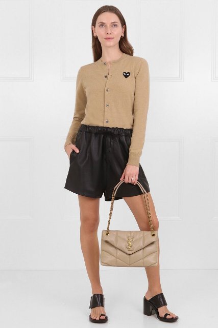 With black leather shorts, beige button down shirt and black mules