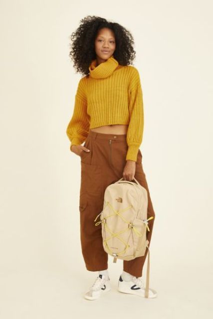 With brown loose pants, beige and yellow backpack and black and white sneakers