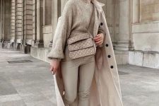 a neutral winter outfit with a tan sweater, tan leather leggings, white chunky boots, a coat and a bag