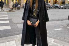 an all-black winter outfit wiht a leather blazer, jeans, chunky Chelsea boots, a coat and a bag
