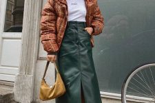 02 a winter look with a white t-shirt, a green A-line midi leather skirt with a front slit, trainers, a rust-colored puffer jacket and a mustard bag