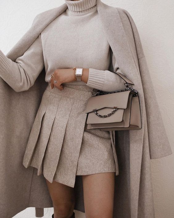 a neutral outfit with a white turtleneck, a wide pleated asymmetrical mini, a grey coat, a grey mini bag