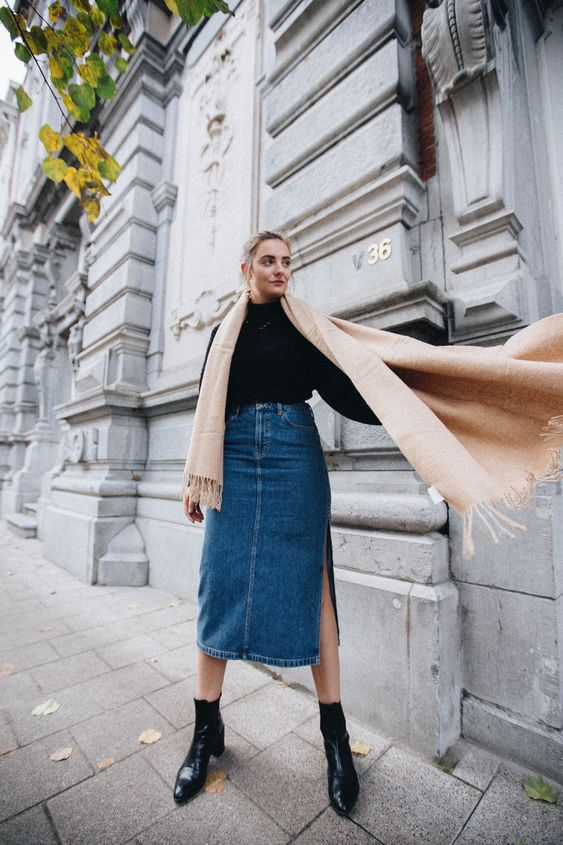 a black turtleneck, a blue denim midi with a side slit, a neutral scarf and black booties