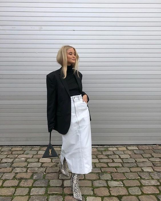 a trendy winter outfit with a black turtleneck and an oversized blazer, a white denim midi, snakeskin print boots and a black bag