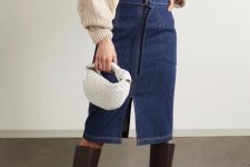 29 a trendy look with a creamy oversized cardigan as a shirt, a blue high waisted denim midi, brown knee boots and a white woven bag