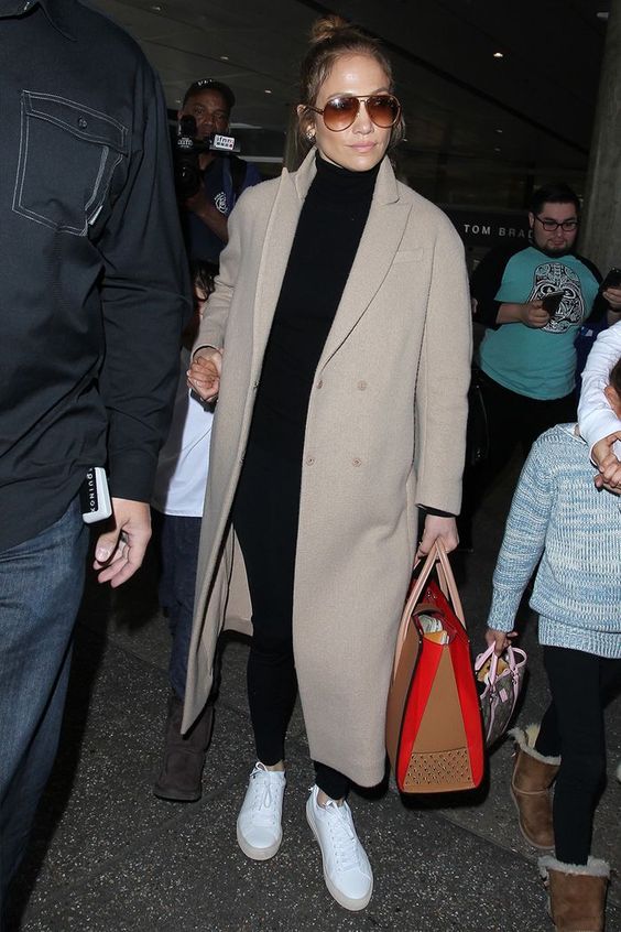 J.Lo wearing a black turtleneck, black leggings, white sneakers, a tan midi coat for a super comfortable look